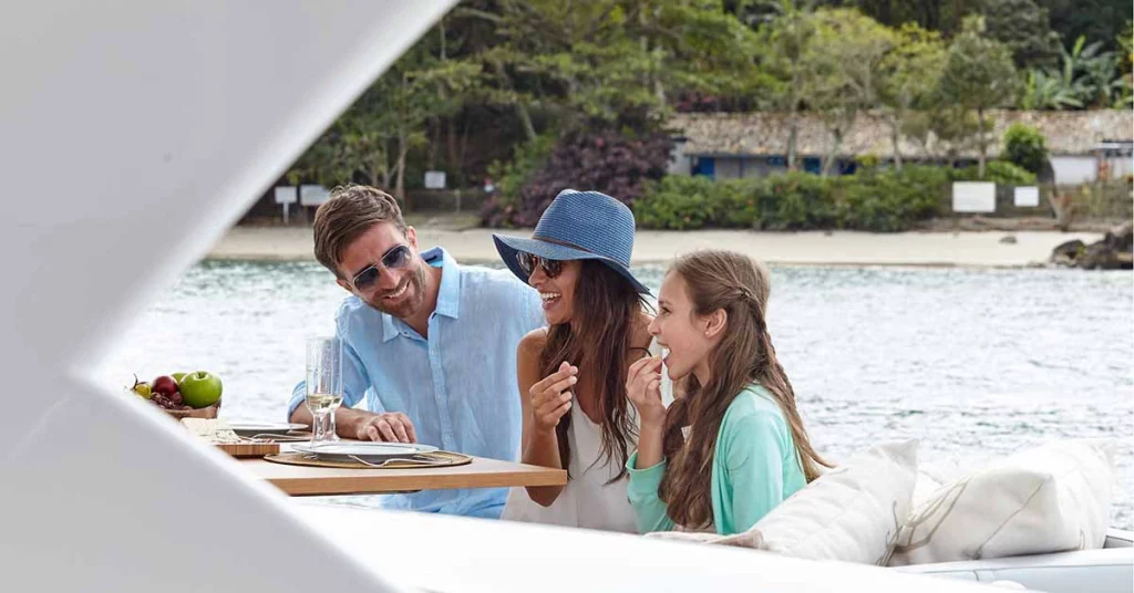 Family enjoying dinner on a boat, sharing a meal together while taking in the scenic waterfront views.